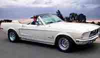 White convertible 1966 Mustang chauffer cruising down the highway